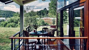 Une terrasse en bois avec une table et des chaises, offrant une vue sur un paysage verdoyant et luxuriant.