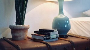 Une table de chevet avec une lampe, une plante en pot et une pile de livres.