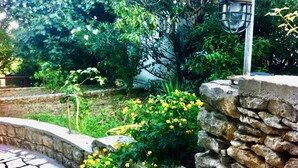 A stone wall with a metal lamp post, surrounded by greenery and flowering plants. - Dunja Apartments (Medulin)