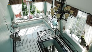 A room with a high ceiling, a staircase, and a view of greenery outside. - Sky Cottage (Rayong)