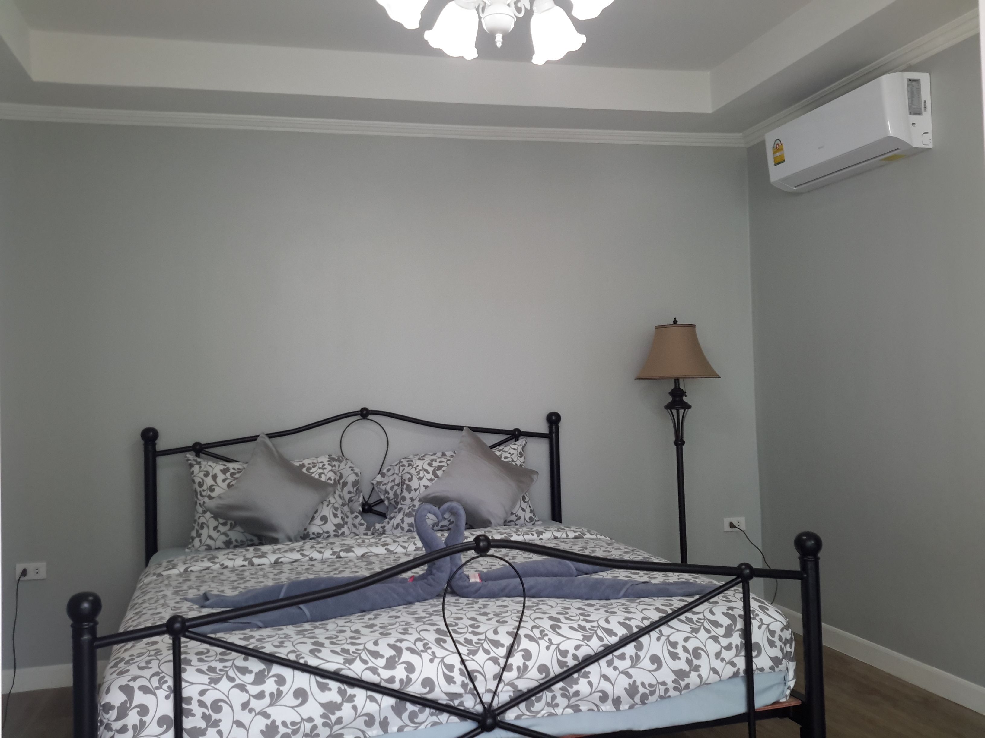 Un dormitorio con cama, lámpara de noche y aire acondicionado en la pared.