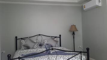 Un dormitorio con cama, lámpara de noche y aire acondicionado en la pared.