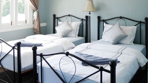 A bedroom with two beds, a chandelier, a window with curtains, and a bedside lamp. - Sky Cottage (Rayong)