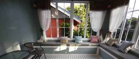Una habitación soleada con una butaca junto a la ventana, una mesa y suelo estampado.