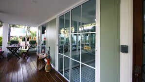 A covered porch with wooden flooring, a table, chairs, and a decorative vase. - Sky Cottage (Rayong)