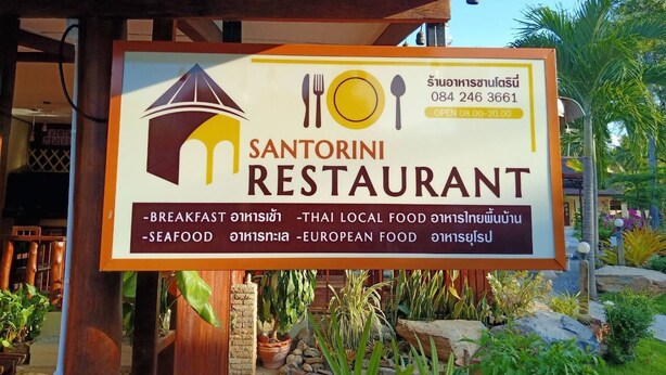 A restaurant signboard with the name 'Santorini Restaurant' and mentions breakfast, seafood, and European food. - Santorini Khanom (Khanom)