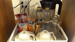 A kitchen area with a coffee maker, tea kettles, and various food items. - Santorini Khanom (Khanom)