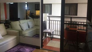 Un salon avec un canapé, une petite table et un balcon doté d’une balustrade.