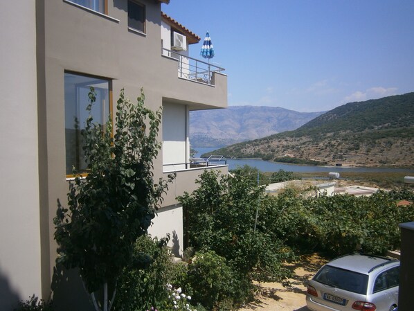Un edificio moderno de dos pisos con un balcón que da a un lago y montañas.