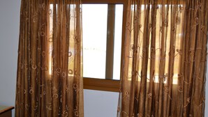 Une chambre avec un lit, une fenêtre avec des rideaux et une vue sur l’extérieur.