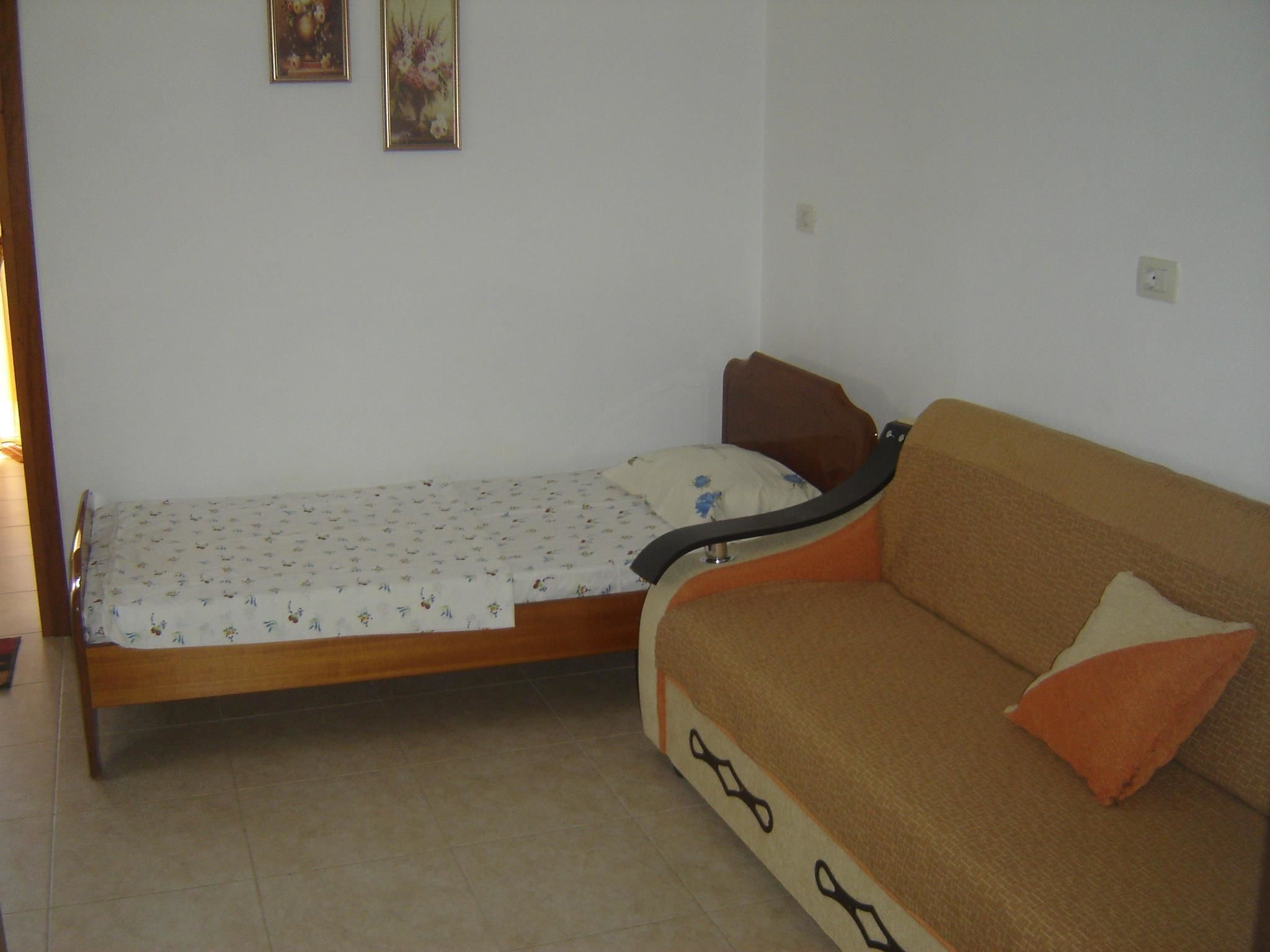 Une petite pièce comprenant un lit, un canapé et deux tableaux accrochés au mur.