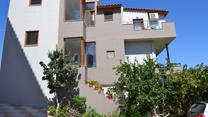 Un immeuble à plusieurs étages doté de balcons, de grandes fenêtres et de plantes en pot.