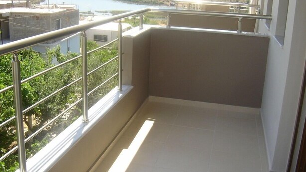 Un balcon doté d’une rambarde en métal, donnant sur une étendue d’eau et sur de la végétation.