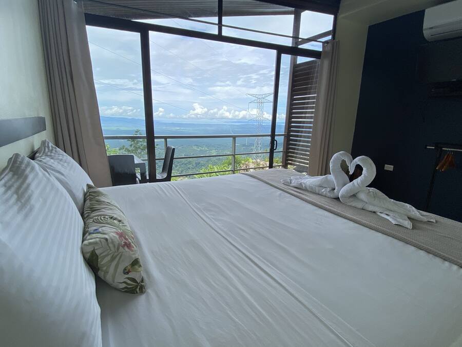 A hotel room with a large bed, a view of the landscape, and a balcony.