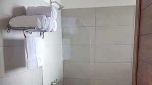 Een badkamer met toilet, douche met glazen deur en wastafel met handdoekhouder.