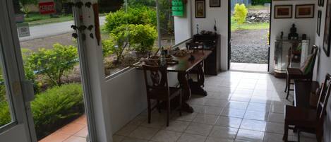 Zona de menjador amb una finestra gran, taula, cadires i vistes a vegetació a l'exterior.