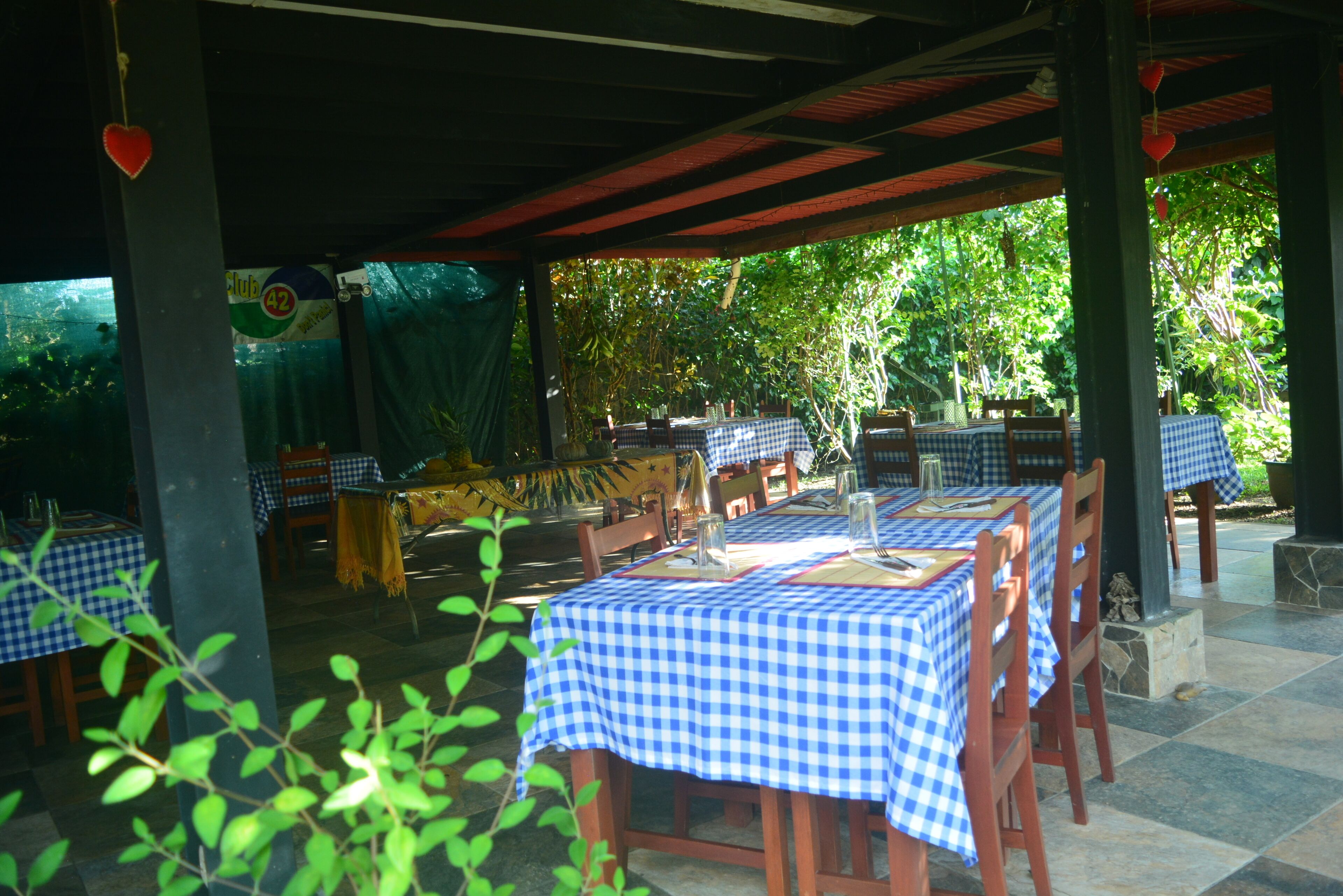 An outdoor restaurant with checkered tablecloths, wooden chairs, and a covered patio area.