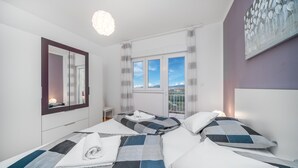 Quarto com duas camas, uma janela grande, um espelho e um quadro na parede.