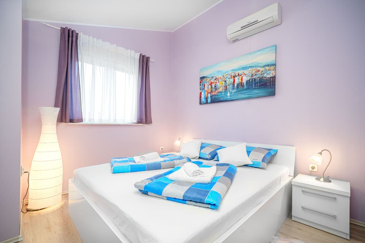 A bedroom with a bed, bedside tables, a lamp, and a painting on the wall.