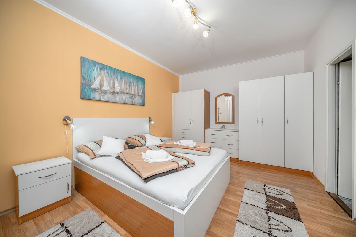 A bedroom with a bed, nightstands, a dresser, a mirror, and a painting on the wall.