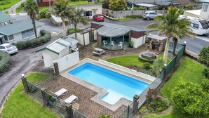 Una proprietà residenziale con piscina, patio coperto e giardino recintato.