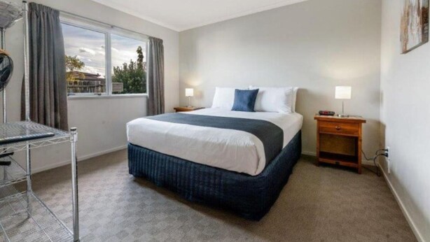 Una camera d'hotel con un letto grande, due comodini, una finestra con tende e vista sull'esterno.