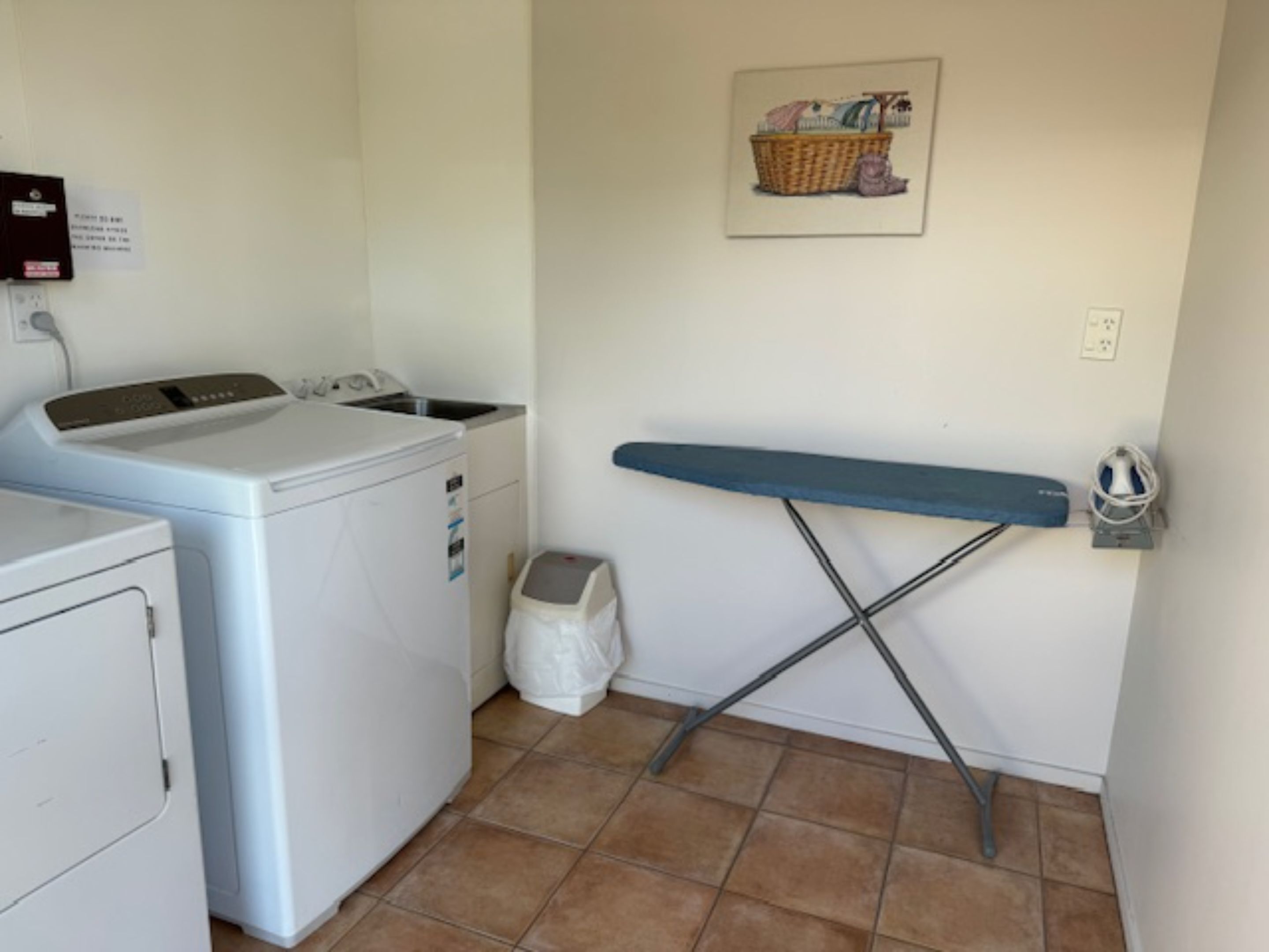 A laundry area with a washing machine, dryer, and ironing board.