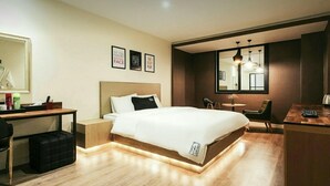 A modern hotel room with a large bed, a desk, and a chair. There are framed motivational posters on the wall. - The Hotel Changwon (Changwon)