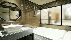 A modern bathroom with a large mirror, a white sink, and a bathtub. - The Hotel Changwon (Changwon)
