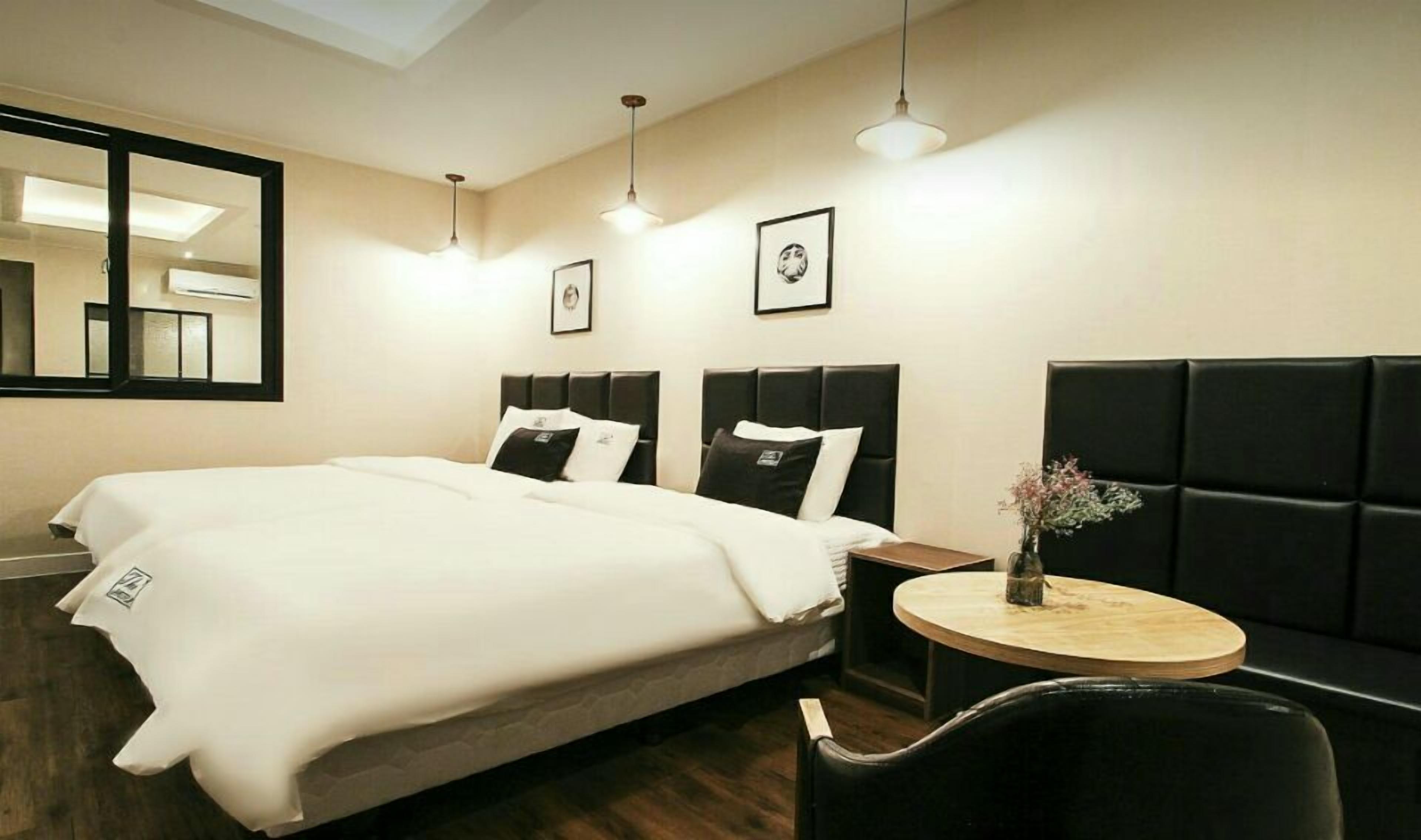 A hotel room with a large bed, two bedside tables, a small round table, and a mirror.