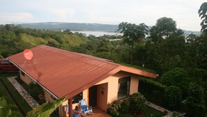 Una casa con techo rojo, un patio con dos sillas y una antena parabólica.