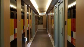 A hotel corridor with lockers, doors, and a carpeted floor.