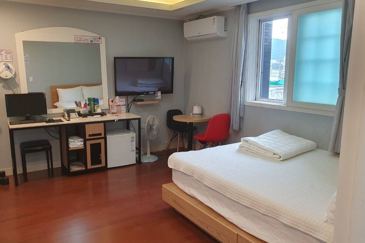 Ein Hotelzimmer mit Bett, Schreibtisch, Stuhl und Fernseher.