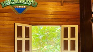 A wooden room with a bed, a window with shutters, and a logo for 'Hilamito Lodge'.