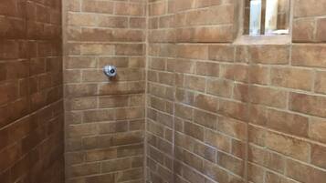 A small, enclosed shower area with brick walls and a tiled floor.