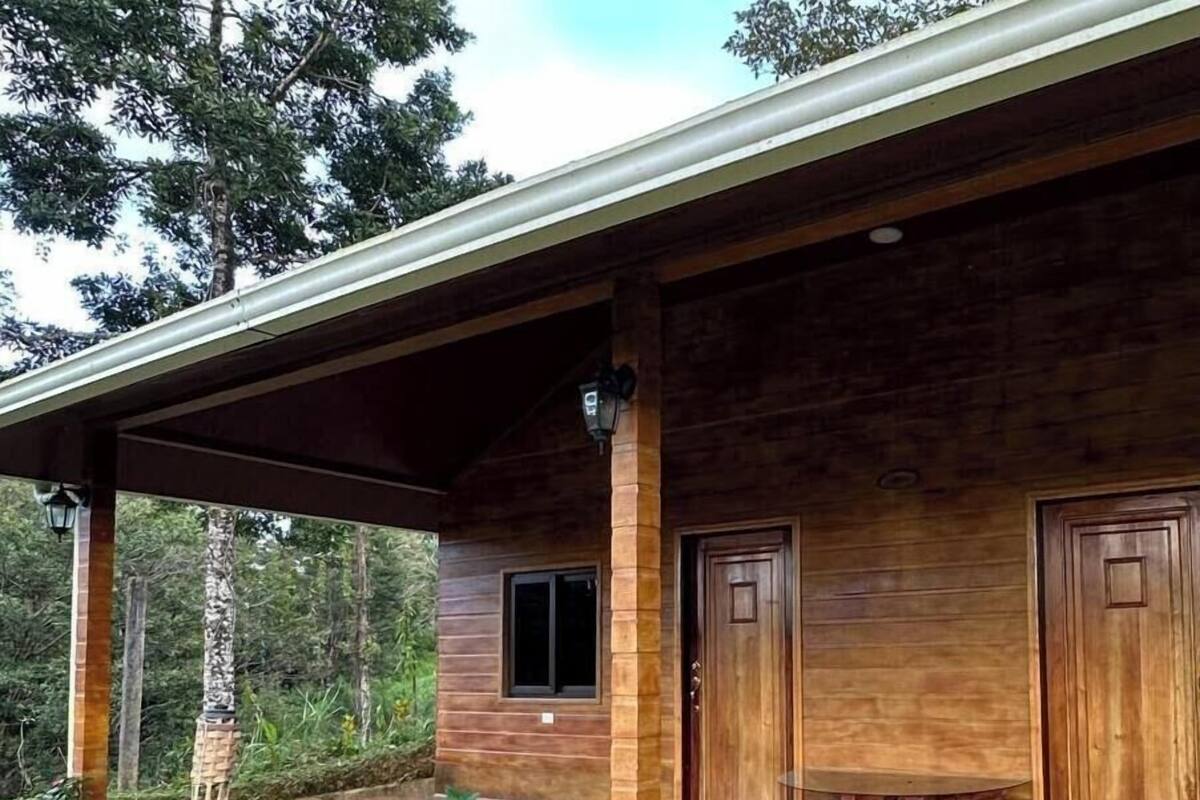 Eine Holzhütte mit einer überdachten Veranda, einem Fenster und zwei Türen.