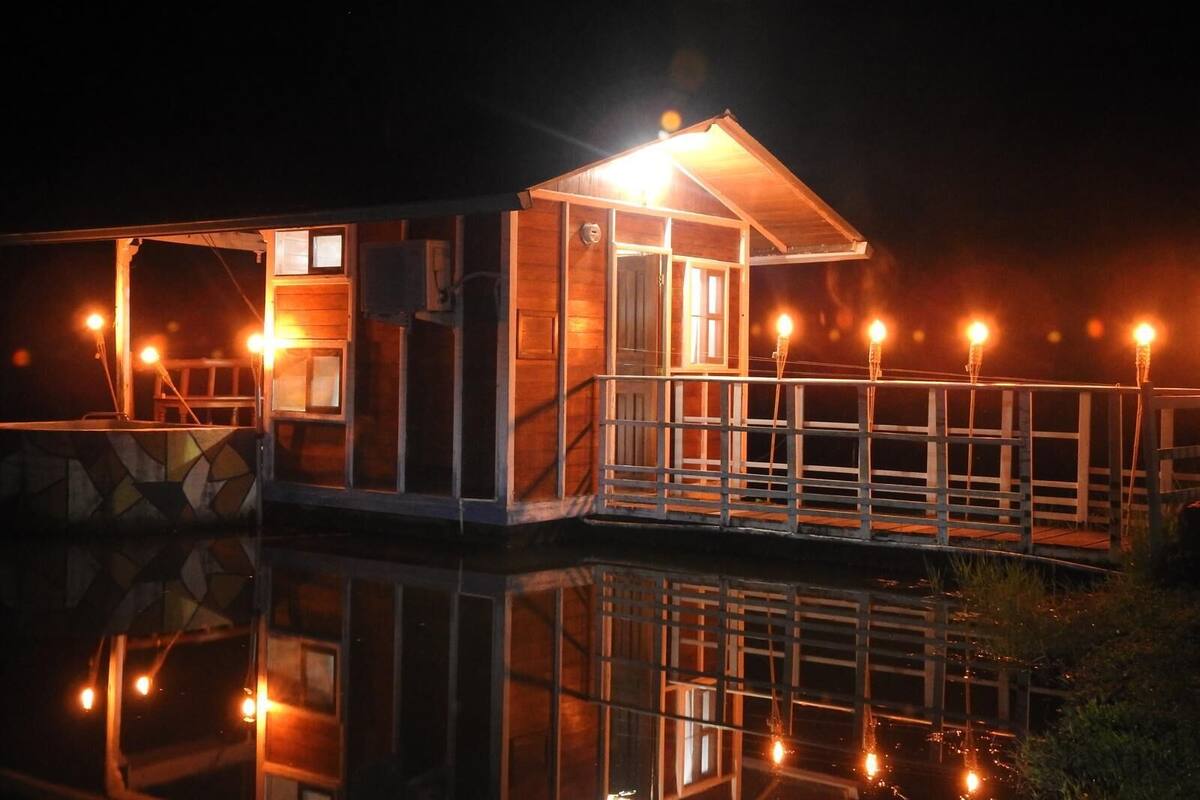 Eine Holzhütte mit Balkon, einer kleinen Veranda und einem Spiegelbild im Wasser.