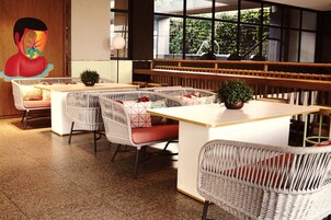 Un restaurant moderne avec des meubles en osier, un îlot central et de grandes fenêtres donnant sur l’extérieur.