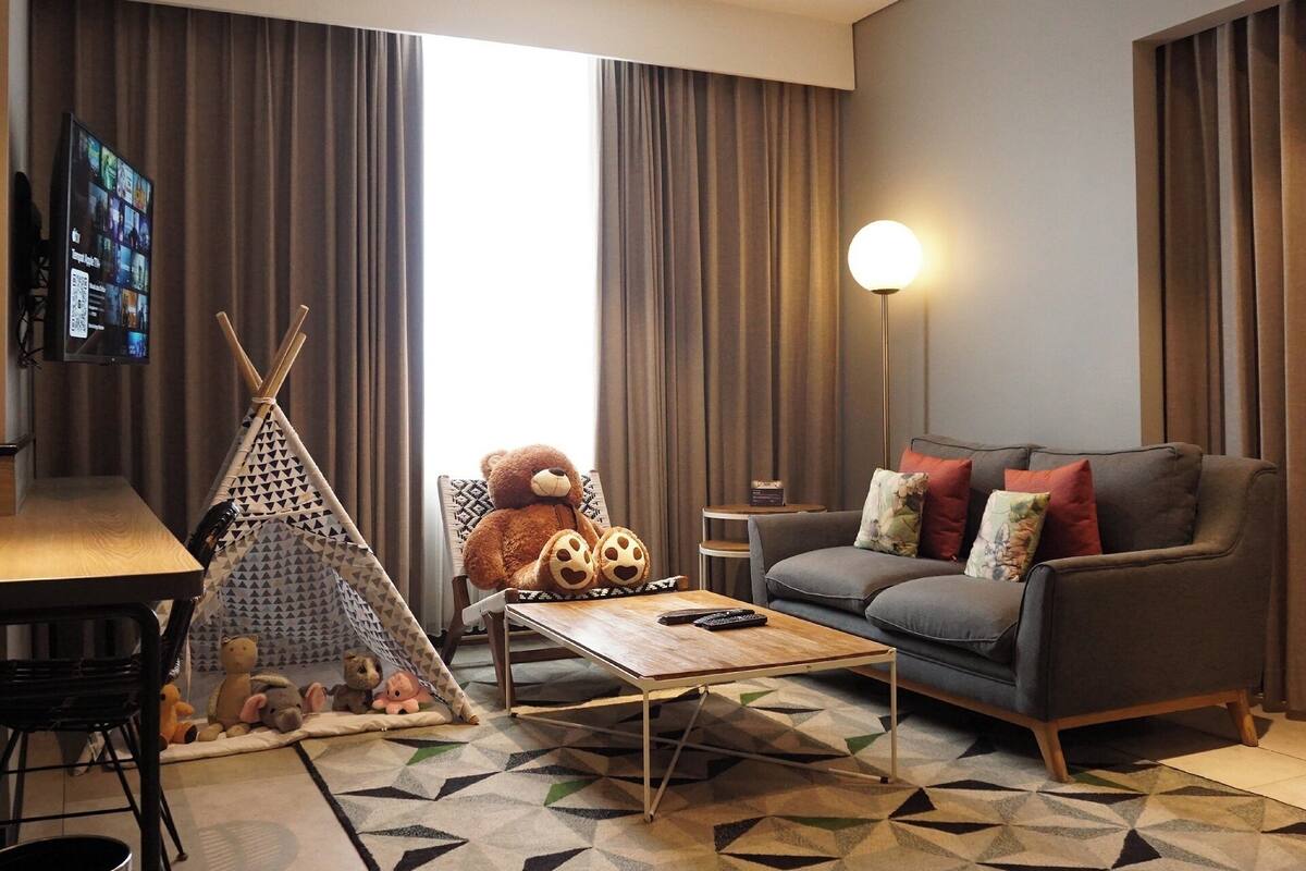 A modern living room with a sofa, a coffee table, a TV, a lamp, and a teepee.