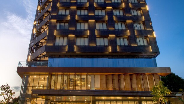 A modern hotel with a unique geometric facade, large windows, and a visible entrance area with a sign. - ARTOTEL Yogyakarta (Depok)