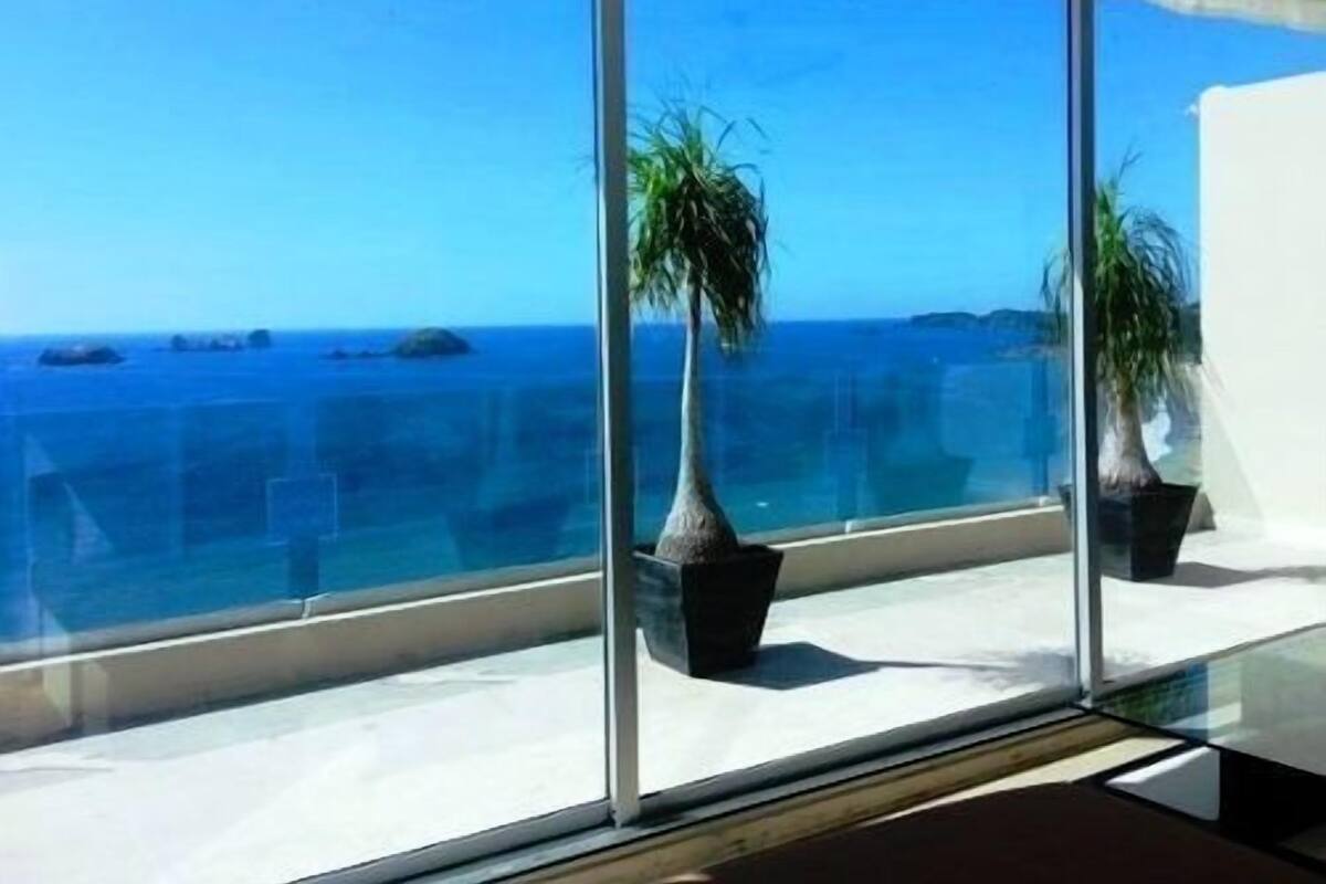 A balcony with a clear view of the ocean and distant islands.