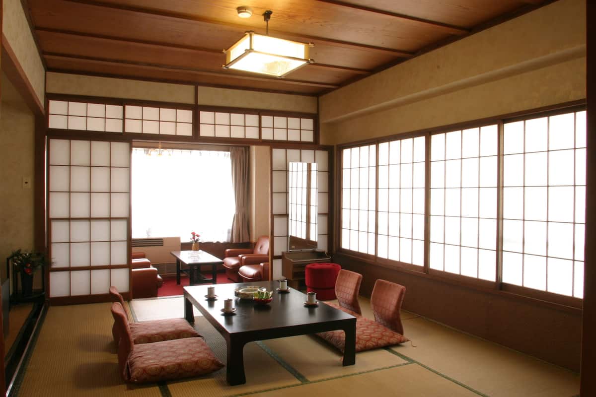 A traditional Japanese room with tatami flooring, a low table with cushions, and sliding doors.