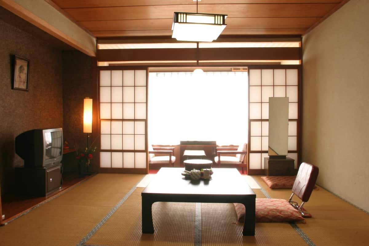 A traditional Japanese room with tatami flooring, a low table, and a television on a cabinet.