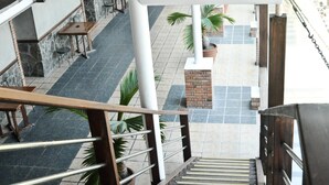 Un espacio interior de varios niveles con una escalera, barandillas de metal y suelo de baldosas.