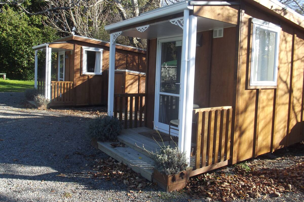 A small wooden cabin with a porch, a window, and a door.
