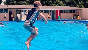A swimming pool with people in the water and a building in the background. - Greytown Campground (Greytown)