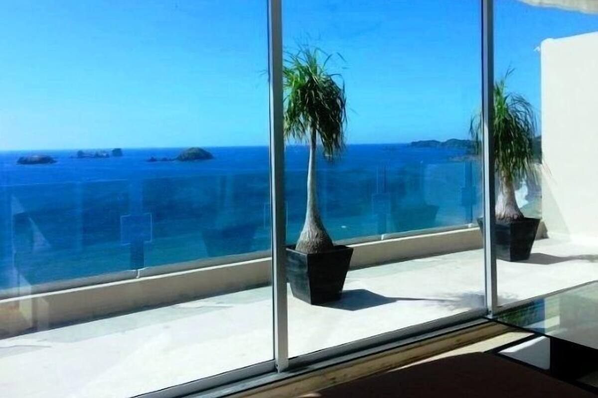 A balcony with a clear view of the ocean and distant islands.