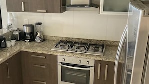 Una cocina equipada con estufa a gas, horno, cafetera y refrigerador.