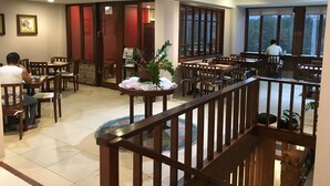 Un restaurant avec des tables et des chaises en bois, un escalier et de grandes fenêtres.