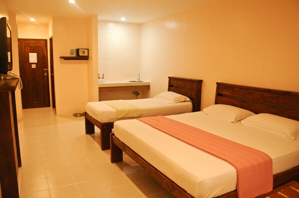 A hotel room with two single beds, a wooden headboard, a small bedside table, a mirror, and a door leading to a hallway. - Mango Valley Hotel 3 (Olongapo)